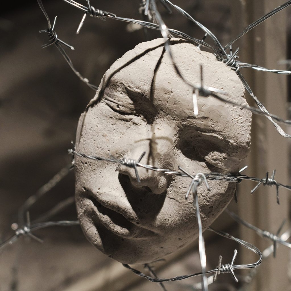 DSC000412 Horizon, 2025: close view of a single plaster cast of the artist's face, eyes closed, a strand of barbed wire pressed across the nose and mouth.