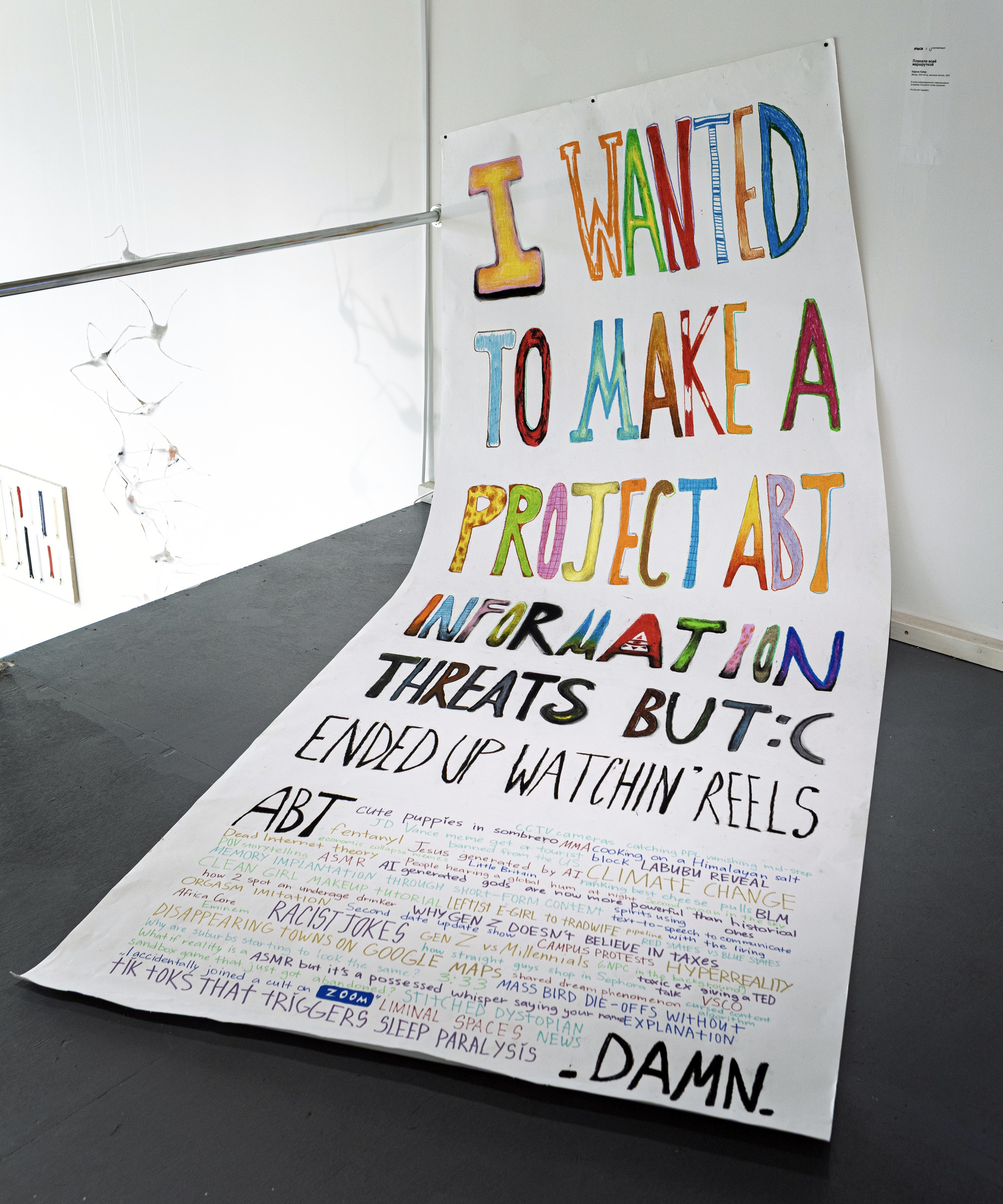 Плакали всей маршруткой, 2025: a three-metre hand-lettered paper banner hanging from a rail and spilling onto the gallery floor.